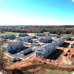 Aerial view of construction site at new apartment complex with forest in the background