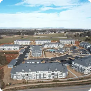 An aerial view of an apartment complex at a road corner, showcasing the layout and surroundings.